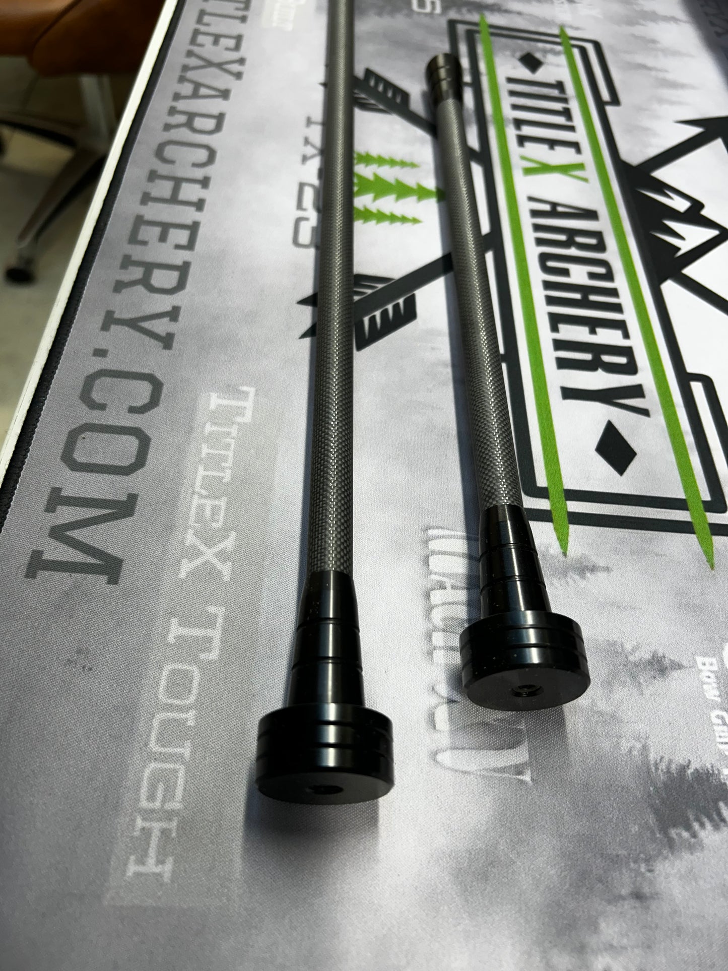 Two black OryX Micro Pro stabilizers for archery, lying on a branded surface.