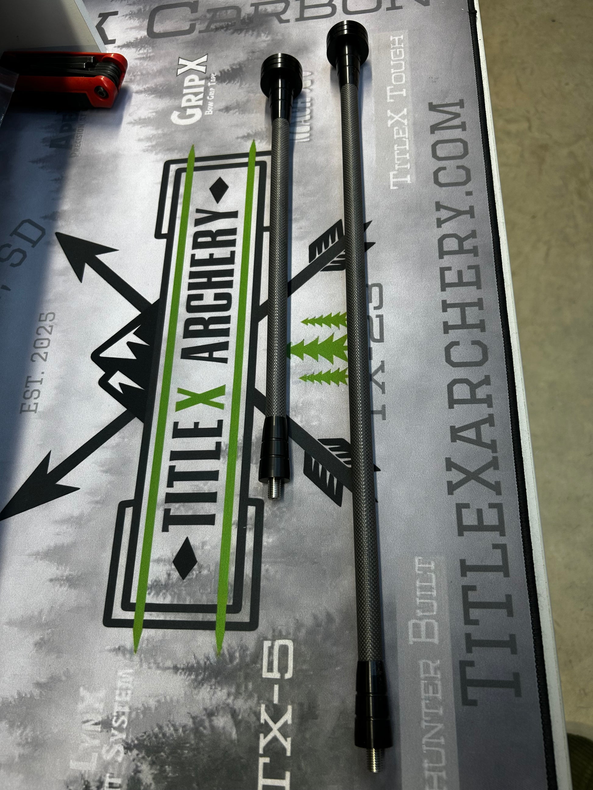 Two black OryX Micro Pro stabilizers with green accents, displayed on a Title X Archery branded surface.