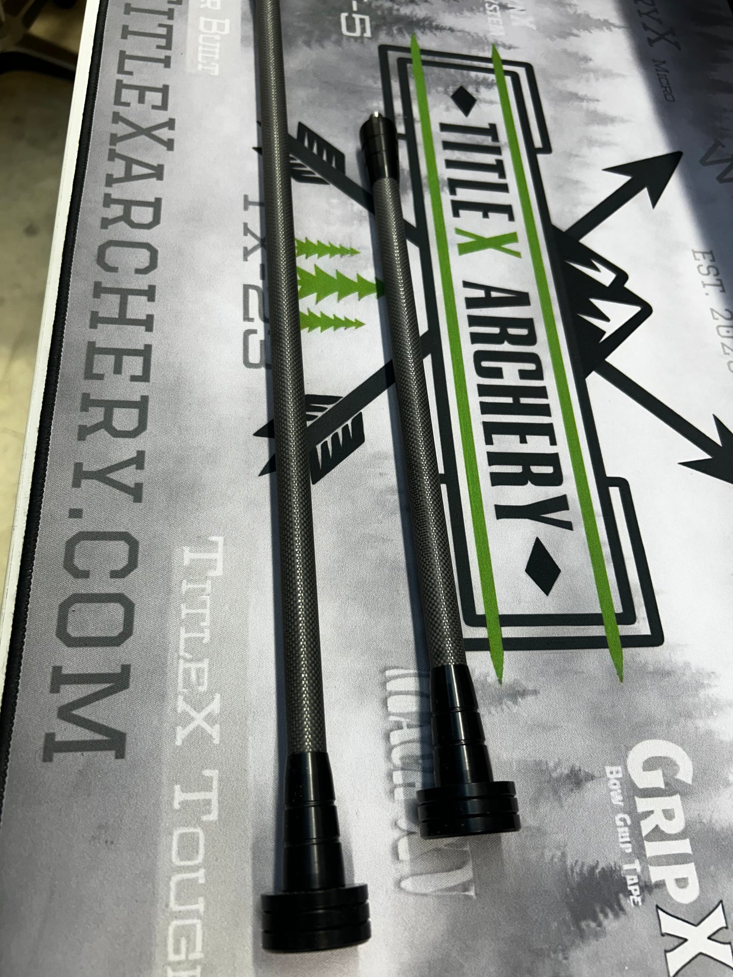 Set of black and green OryX Micro Pro stabilizers for archery, displayed on branded material.