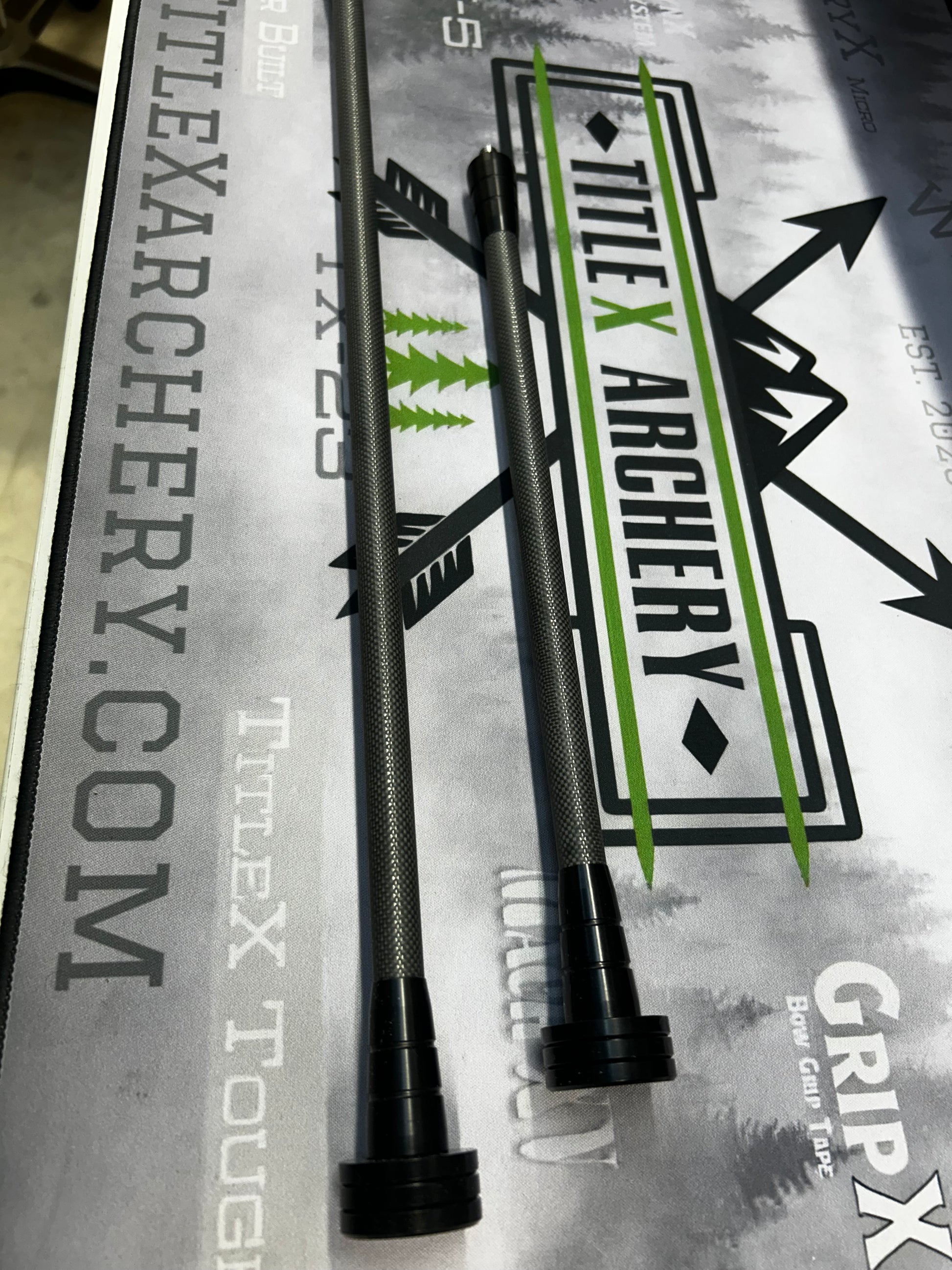 Set of black and green OryX Micro Pro stabilizers for archery, displayed on branded material.