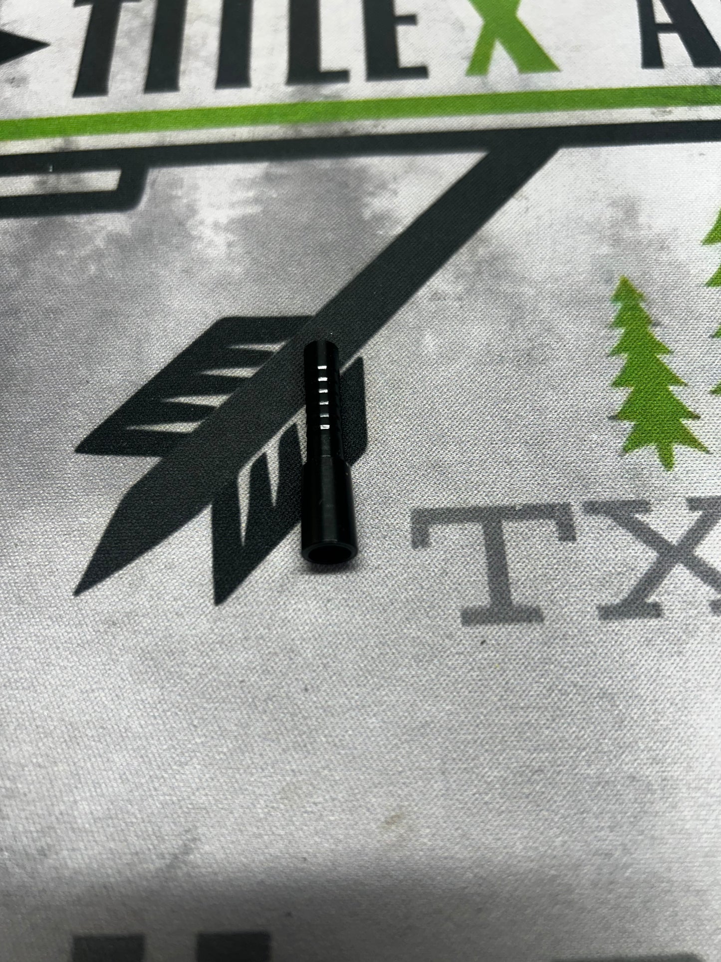 Black aluminum half-out arrow tip, shown on a white fabric background with graphic designs.