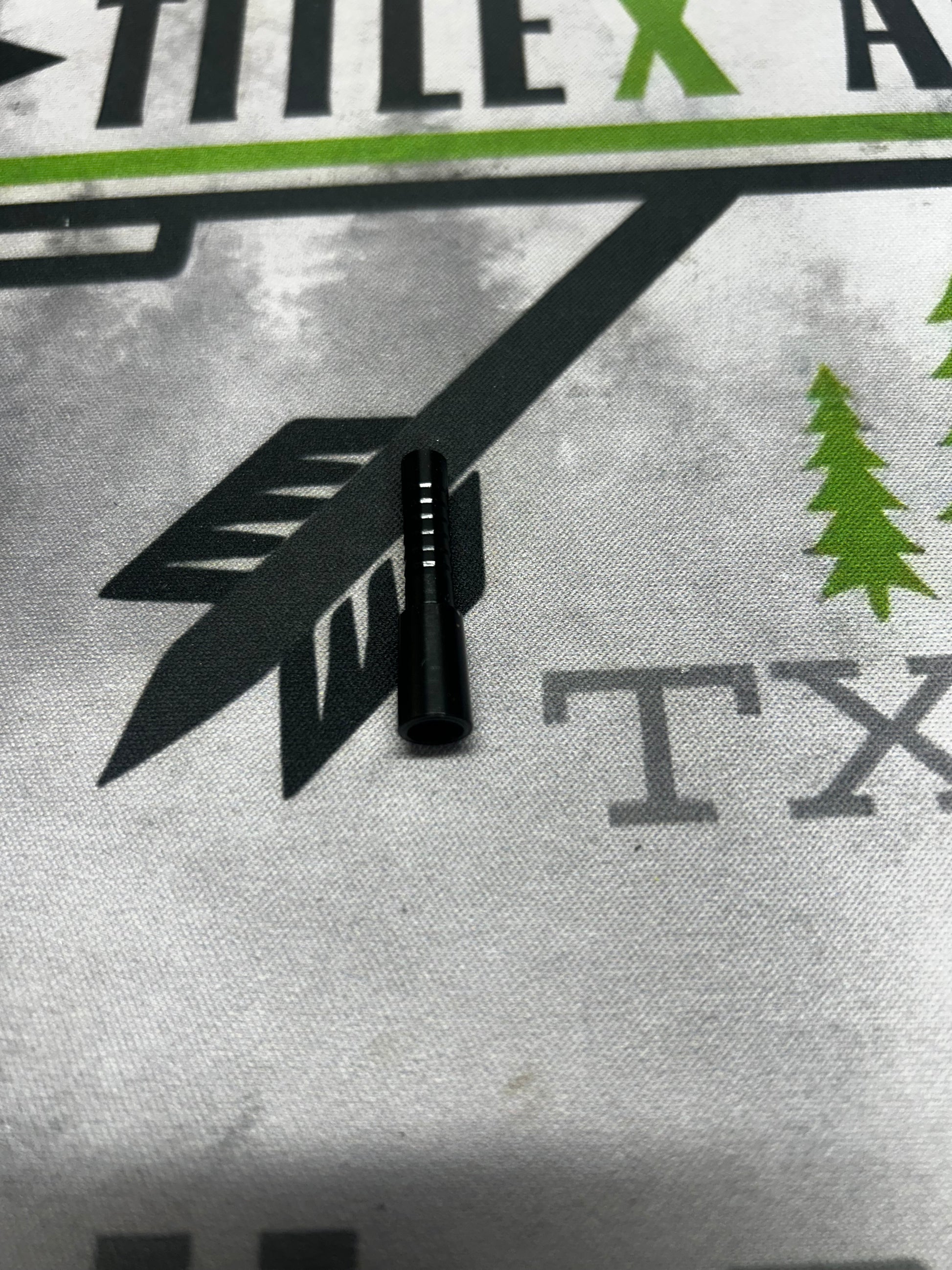 Black aluminum half-out arrow tip, shown on a white fabric background with graphic designs.