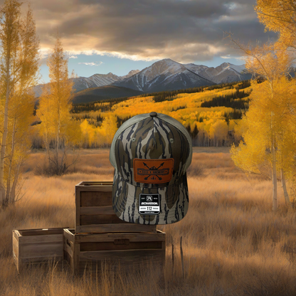 Richardson 112 camo hat on weathered wood, set against golden aspen and mountain backdrop at sunset. | titlex-scene-western-elk